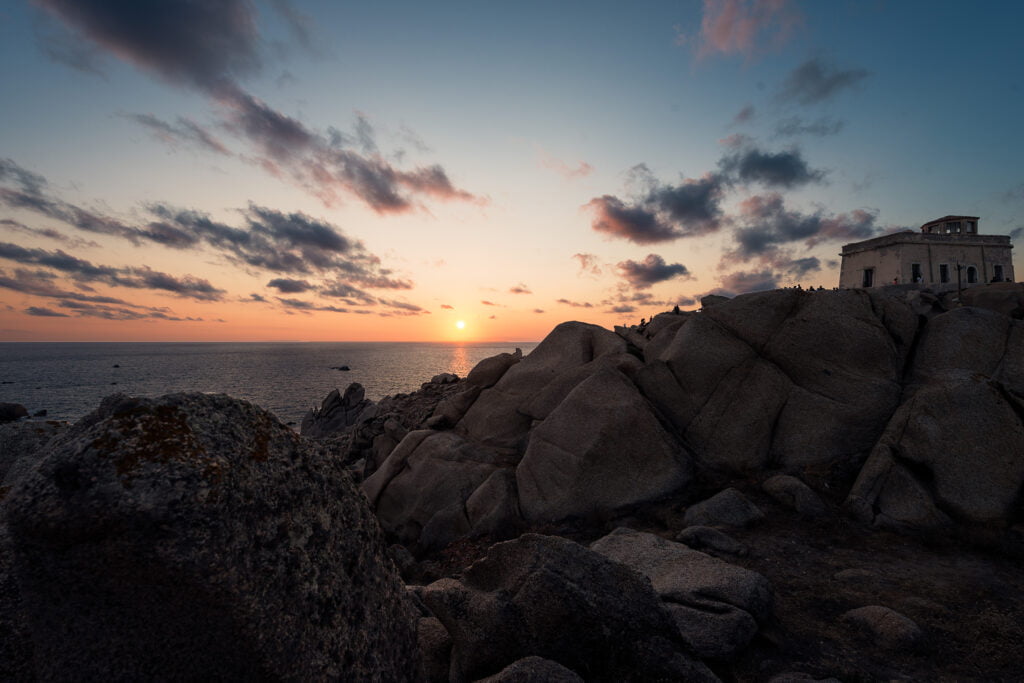 coastal landscape of rocks and thickets at sunset capo testa